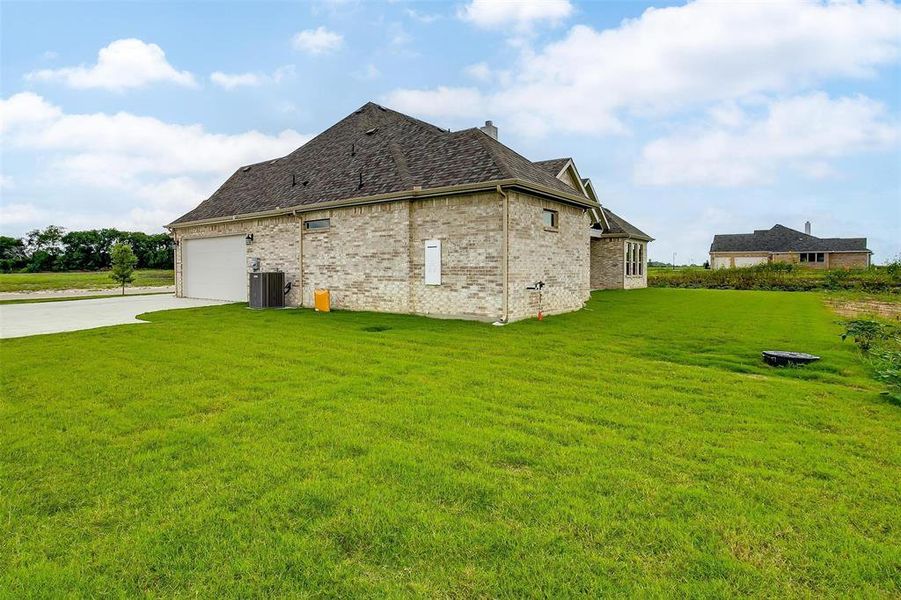 View of side of home featuring a garage, central air condition unit, and a yard