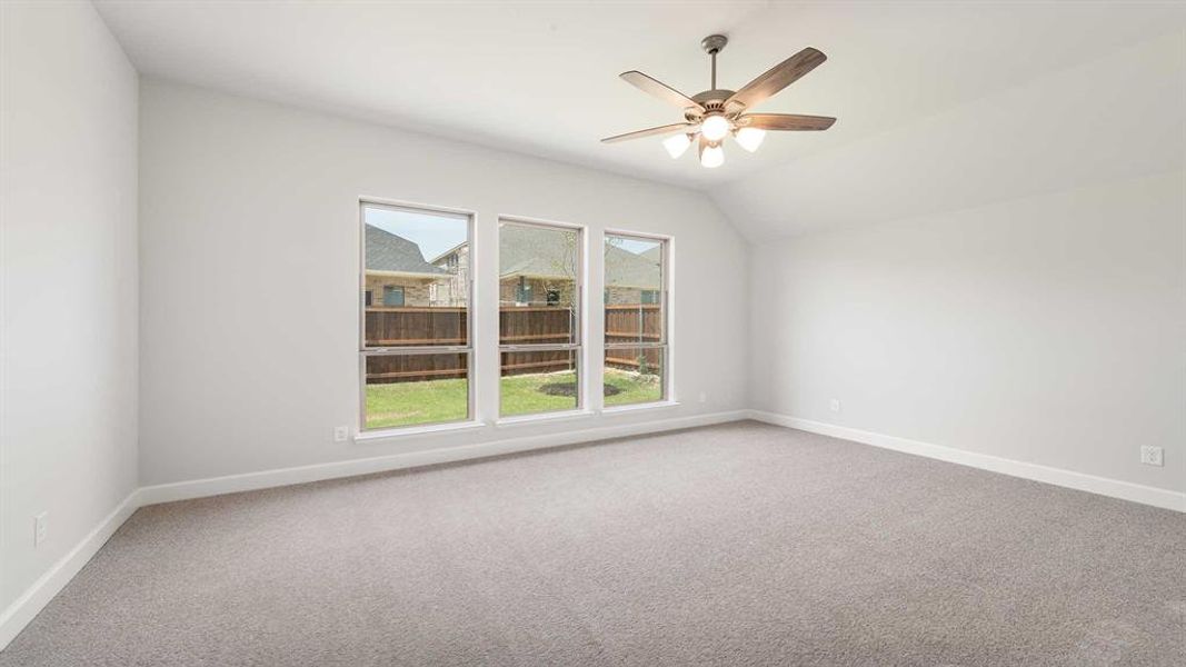 Spare room featuring carpet flooring, ceiling fan, and vaulted ceiling