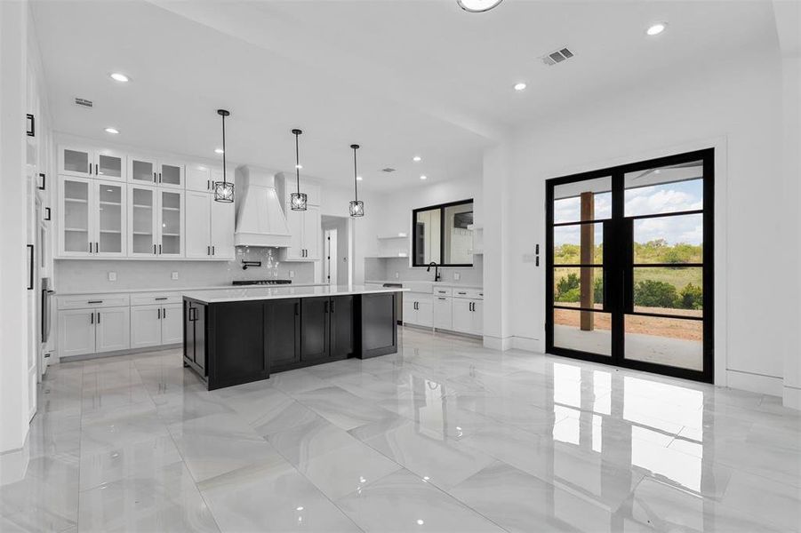 Kitchen featuring custom exhaust hood, light tile patterned floors, and a center island