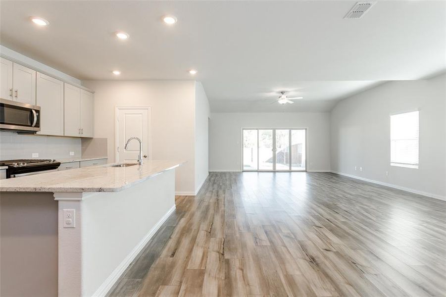 Kitchen featuring luxury vinyl flooring, a center island with sink, white cabinets, sink, and appliances with stainless steel finishes