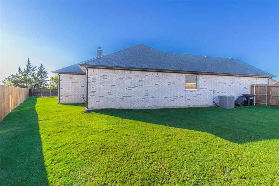 Rear view of property with a lawn and central AC