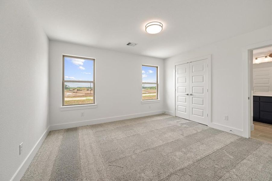 Unfurnished bedroom with a closet, light colored carpet, and ensuite bathroom