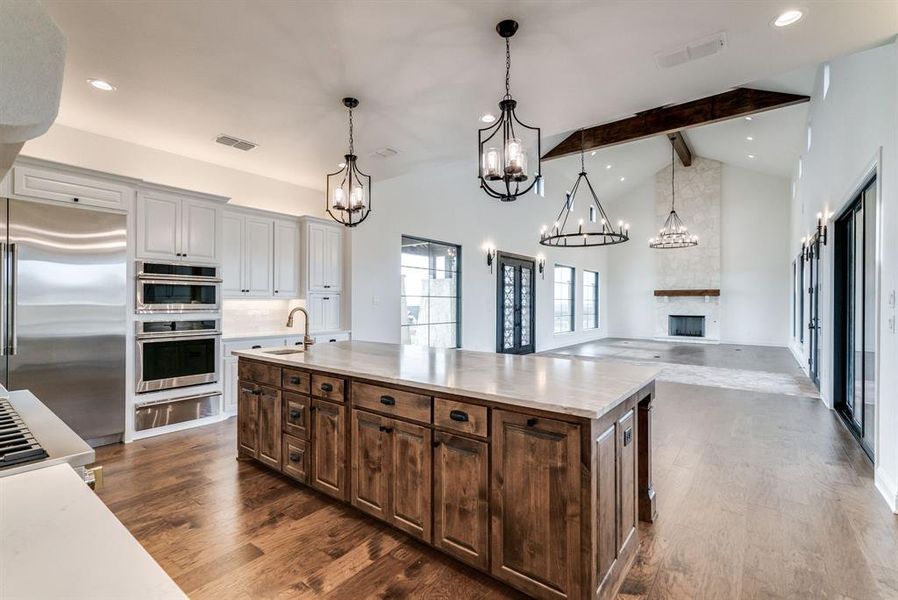 Kitchen with a large island, stainless steel appliances, lofted ceiling with beams, a fireplace, and dark hardwood / wood-style flooring