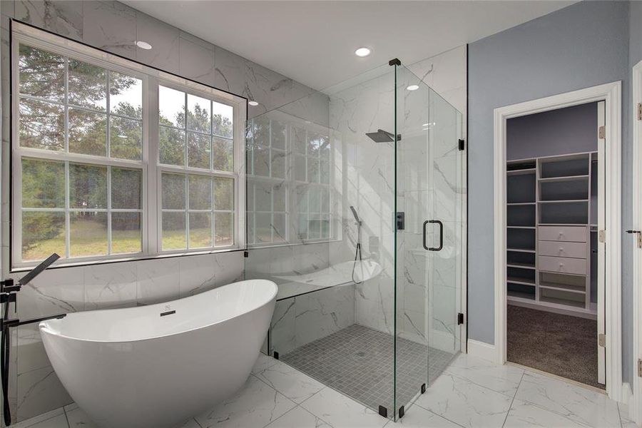 Master bathroom featuring tile patterned flooring, tile walls, shower with separate bathtub, and a wealth of natural light