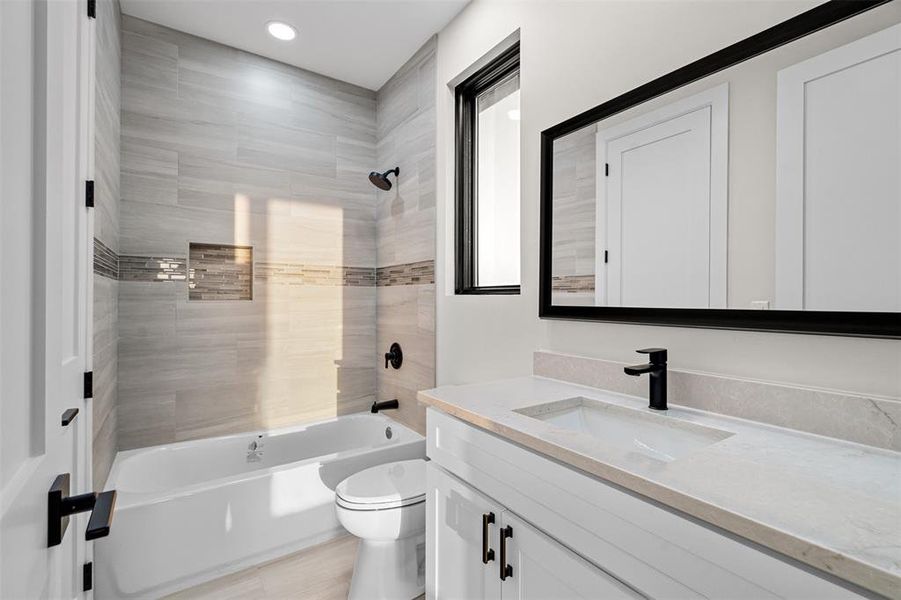 Full bathroom featuring vanity, tiled shower / bath combo, and toilet