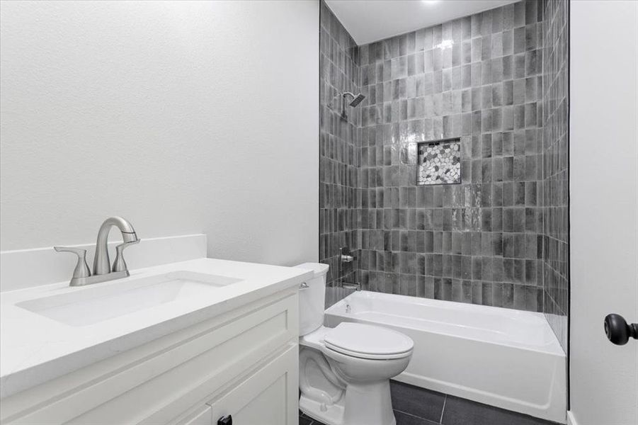 Full bathroom with tiled shower / bath, vanity, toilet, and tile patterned floors