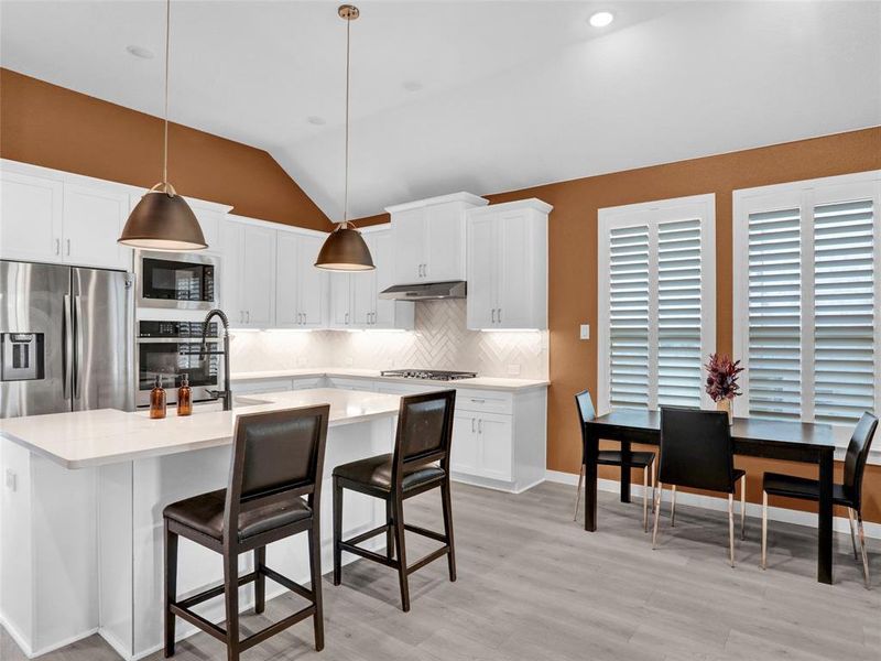 Gorgeous modern kitchen with double ovens, quartz counters, farmhouse sink, island and gas stovetop.