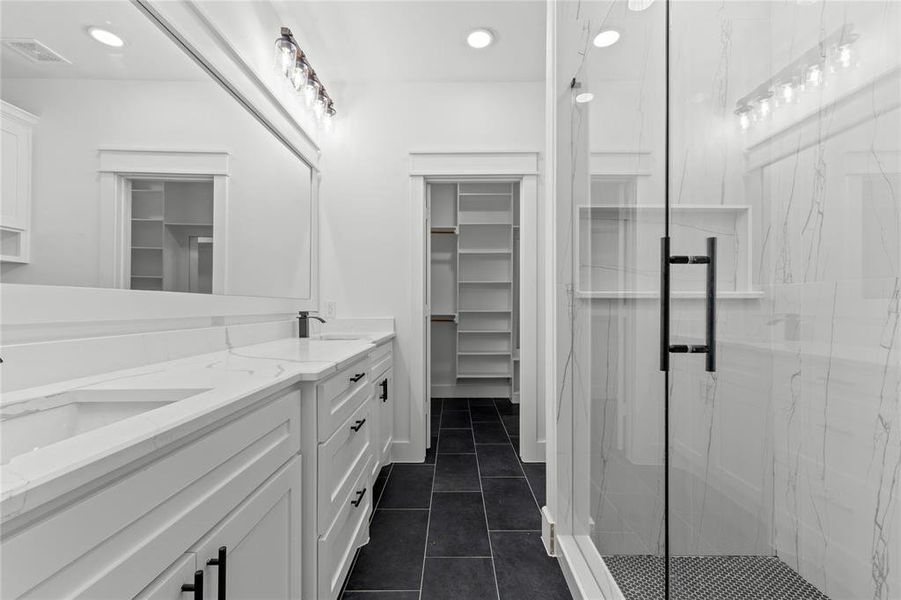 Bathroom featuring vanity, a shower with shower door, and tile patterned flooring