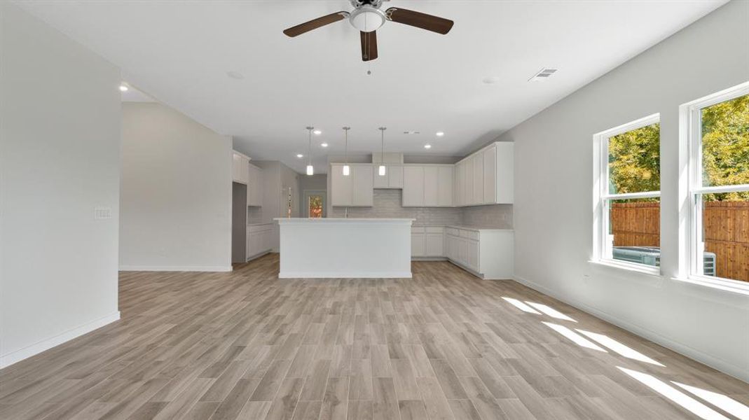 Kitchen with ceiling fan, white cabinets, light hardwood / wood-style floors, and a center island