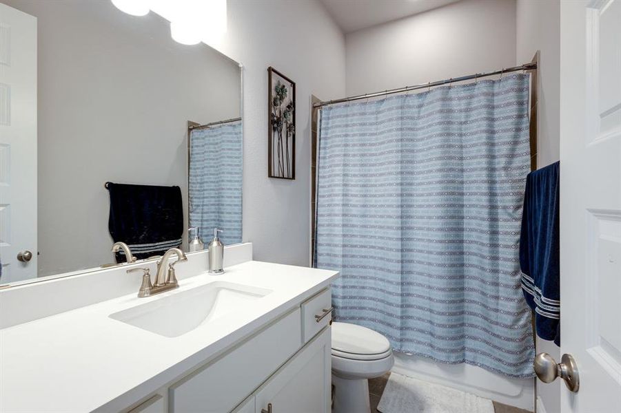 Full bathroom featuring shower / bathtub combination with curtain, tile patterned flooring, vanity, and toilet