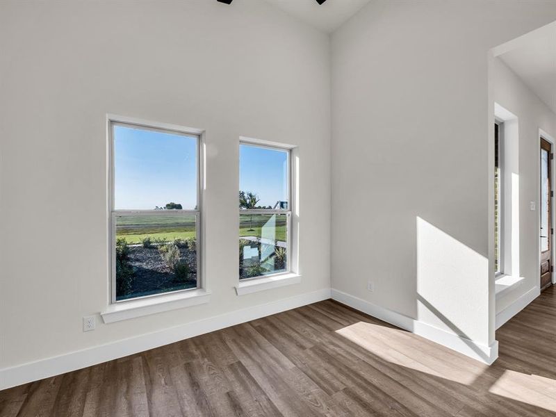 Empty room featuring hardwood / wood-style floors, a towering ceiling, and ceiling fan