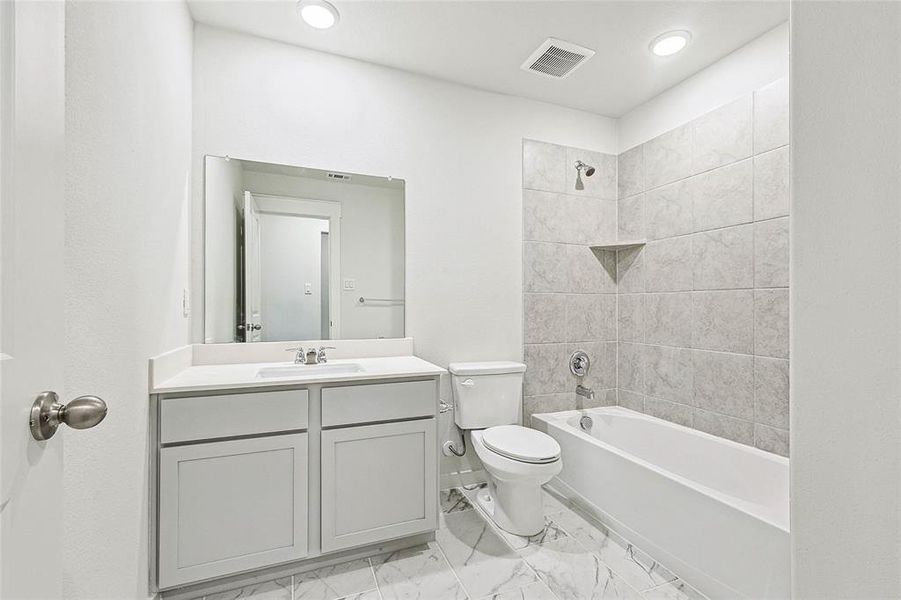 Full bathroom with vanity, tiled shower / bath combo, toilet, and tile patterned floors