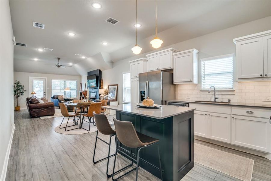 Kitchen with ceiling fan, pendant lighting, white cabinets, stainless steel fridge with ice dispenser, and light wood-type flooring