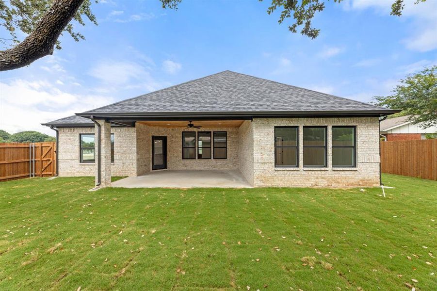 Rear view of house featuring ceiling fan, a lawn, and a patio