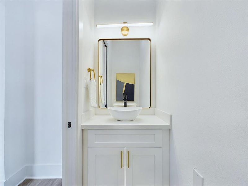 This half-bath that is tucked away at the entryway of the home offers refinement and sophistication. Bronze hardware adorns the sleek cabinetry, a contemporary mirror reflects both style and functionality, while a ceramic bowl sink serves as the statement piece of this space! The added convenience of a pocket door maximizes space without compromising on style, making this guest bathroom a true testament to thoughtful design! *All interior photos are from the model: 9007 Orange Springs Dr.*