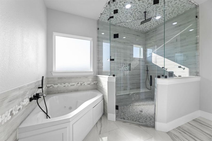 Bathroom featuring jet tub, independent shower with steamer and multiple heads and tile walls