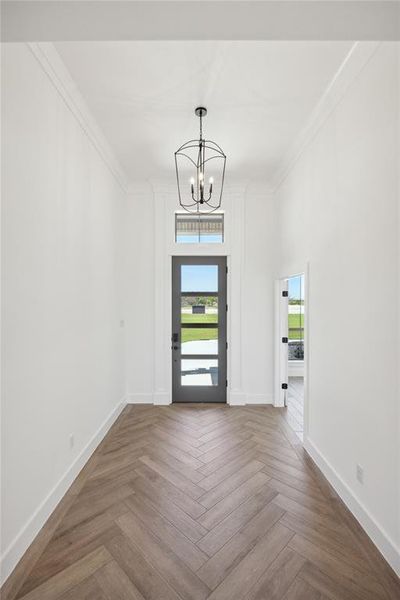 Spare room with crown molding, a chandelier, and parquet floors