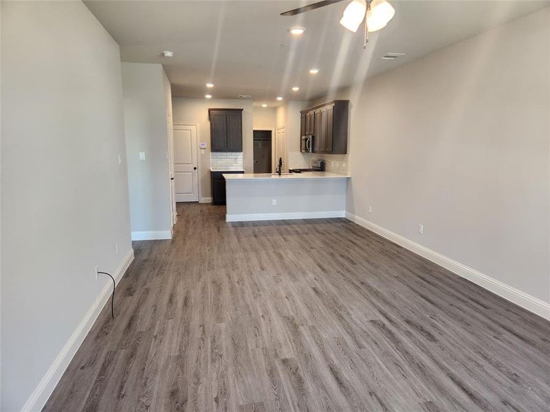 Unfurnished living room featuring sink, wood-type flooring, and ceiling fan