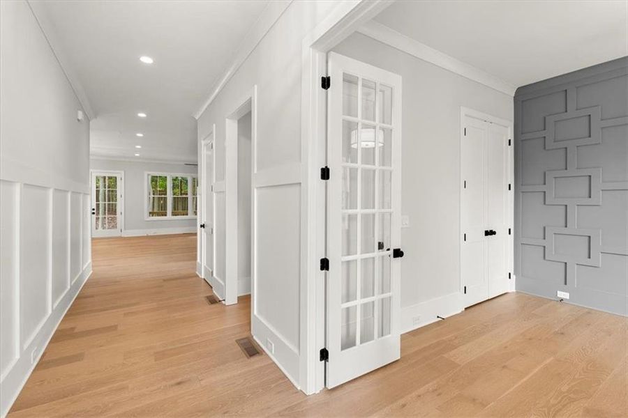 Hall with light hardwood / wood-style flooring and crown molding