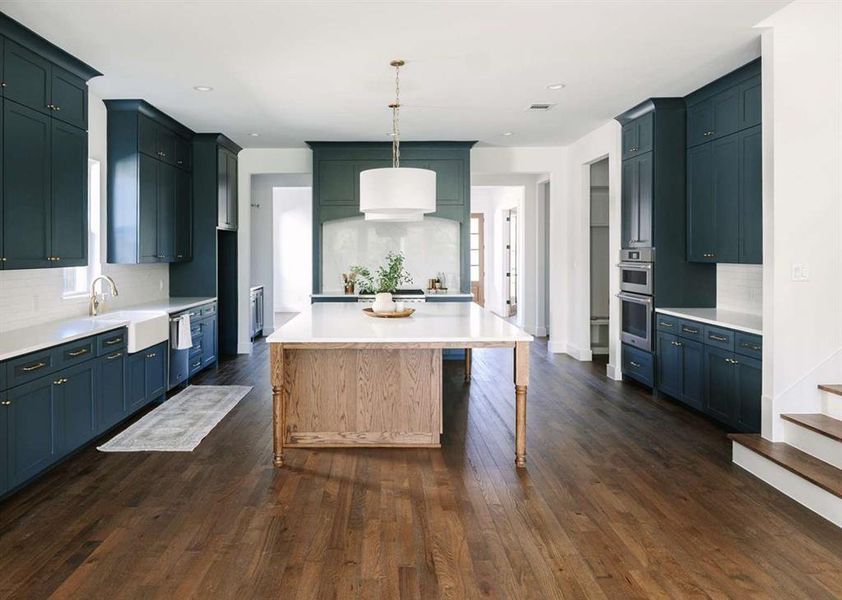 Kitchen with pendant lighting, dark wood-type flooring, sink, backsplash, and double oven