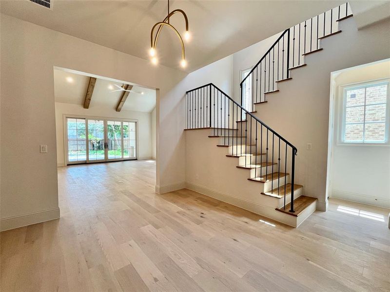 Stairway featuring a chandelier, wood-type flooring, and vaulted ceiling with beams