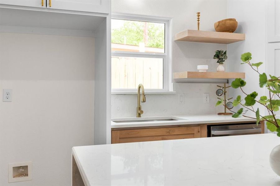 Kitchen featuring white cabinets, tasteful backsplash, sink, and stainless steel dishwasher