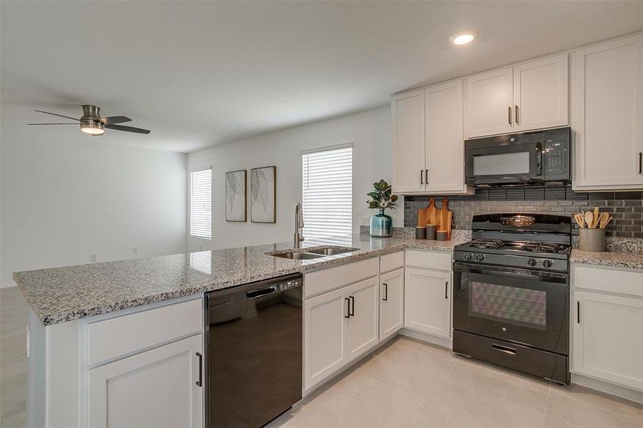 Kitchen with black appliances, kitchen peninsula, backsplash, sink, and ceiling fan