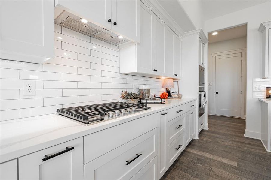 Kitchen featuring white cabinets, tasteful backsplash, extractor fan, appliances with stainless steel finishes, and dark hardwood / wood-style floors