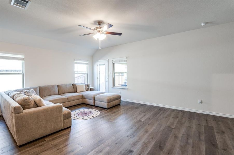 Living room with vaulted ceiling, ceiling fan, and dark hardwood / wood-style flooring