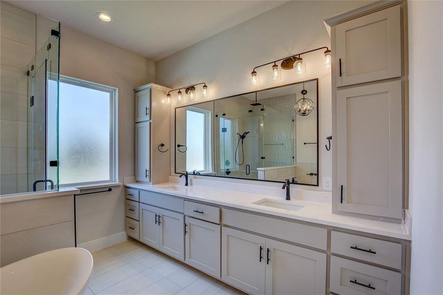 Bathroom with a shower with door, tile flooring, dual sinks, and large vanity