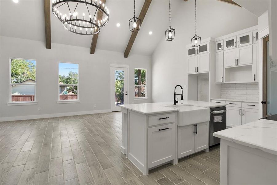 Kitchen with white cabinetry, sink, beamed ceiling, and decorative light fixtures