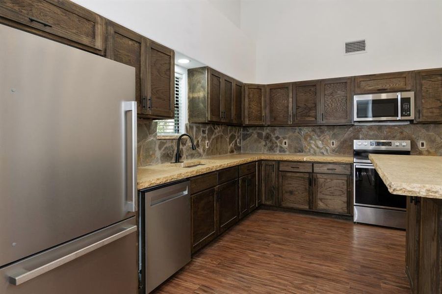 Kitchen with dark brown cabinets, appliances with stainless steel finishes, and dark hardwood / wood-style floors