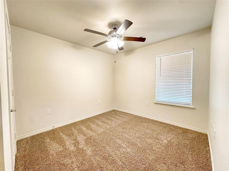 Carpeted empty room featuring ceiling fan