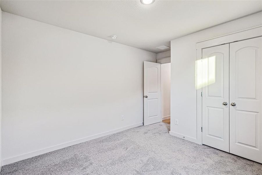 Unfurnished bedroom with light carpet and a closet