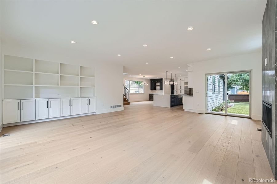 Expansive great room with wall built-in cabinetry is centered around a linear fireplace accent wall while seamlessly transitioning to dual outdoor spaces creating an inviting indoor-outdoor living experience.