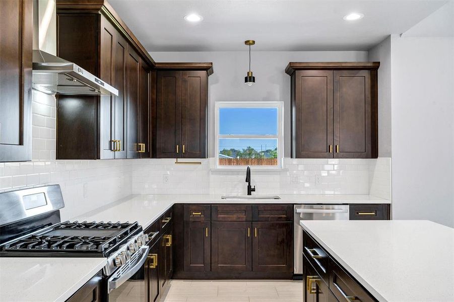 Kitchen with sink, decorative light fixtures, backsplash, wall chimney exhaust hood, and stainless steel appliances