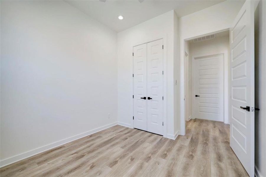 A bright white room featuring wooden floors and elegant white doors, creating a clean and spacious atmosphere.