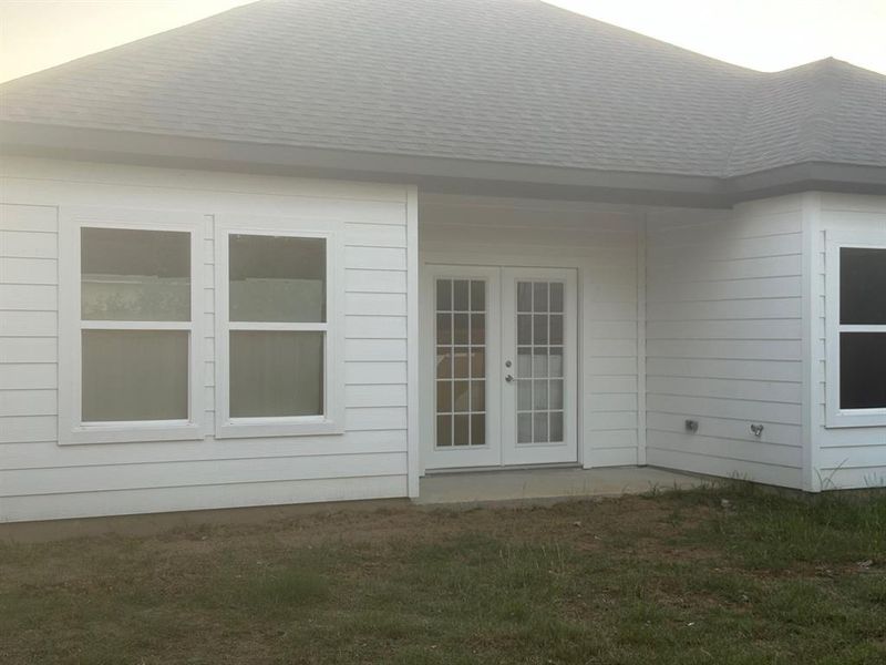 View of side of property with a yard and french doors