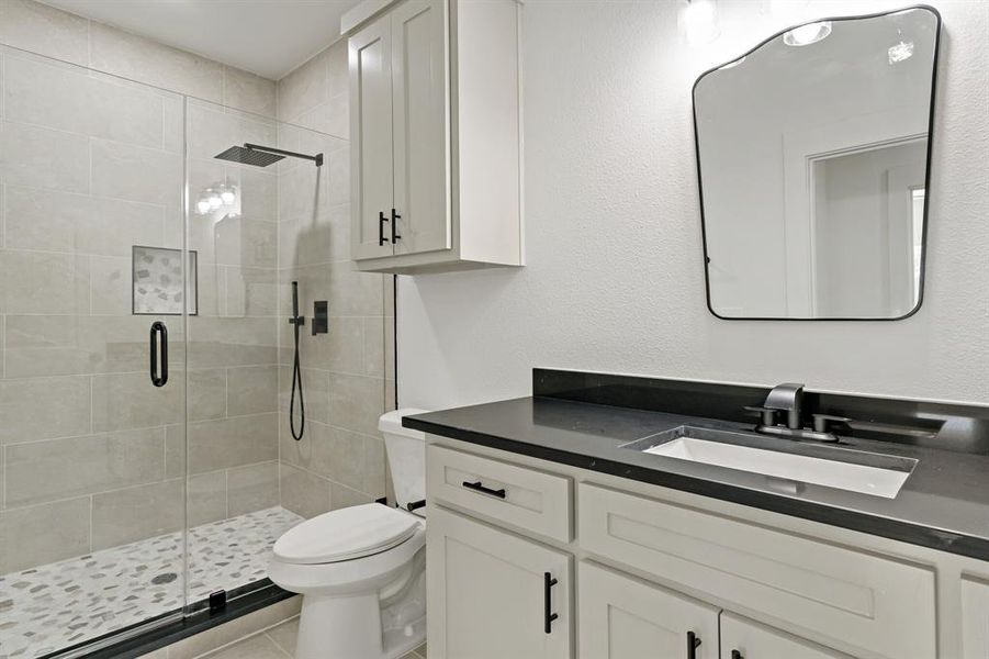 Bathroom with vanity, tile patterned floors, walk in shower, and toilet