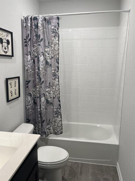 Full bathroom with toilet, vanity, shower / bath combo, and hardwood / wood-style flooring