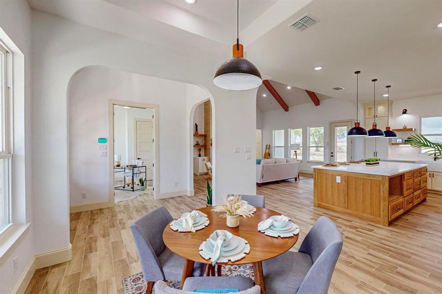 Dining room with light wood-type flooring and lofted ceiling with beams