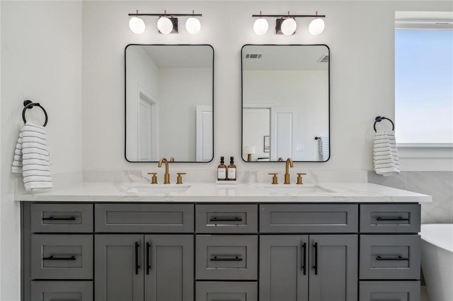 Experience elegance and practicality in this luxurious bathroom, featuring expansive quartz countertops with his-and-hers sinks, ample drawer storage, and generous cabinet space. Designed for ultimate comfort and organized living.