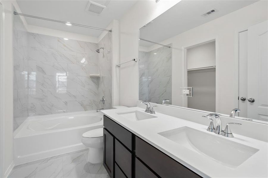 This primary bathroom is definitely move-in ready! Featuring a tub/shower combo, stained cabinets with light countertops, spacious walk-in closet with shelving, high ceilings, custom paint, sleek and dark modern finishes.