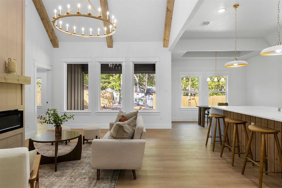 Living room with an inviting chandelier, lofted ceiling with beams, and light wood-type flooring