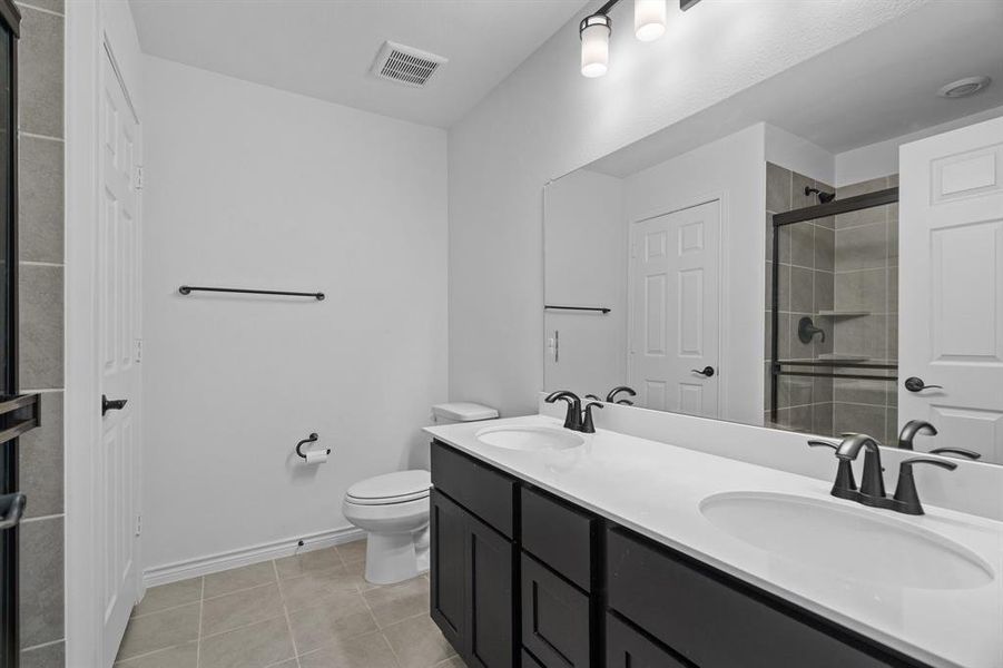 Bathroom featuring walk in shower, tile patterned floors, vanity, and toilet