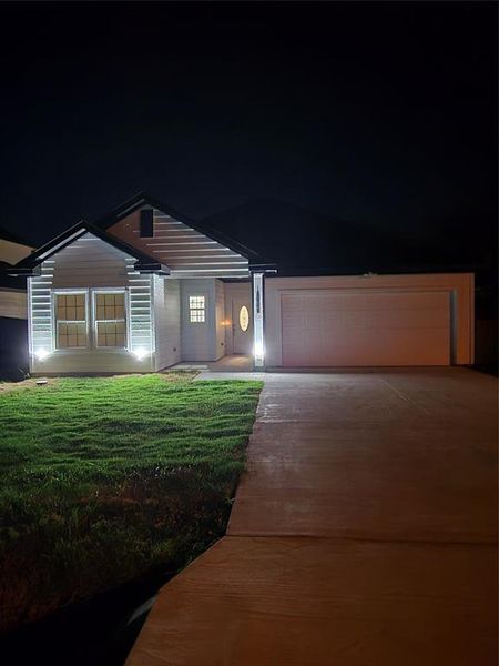 View of front facade featuring a garage and a yard