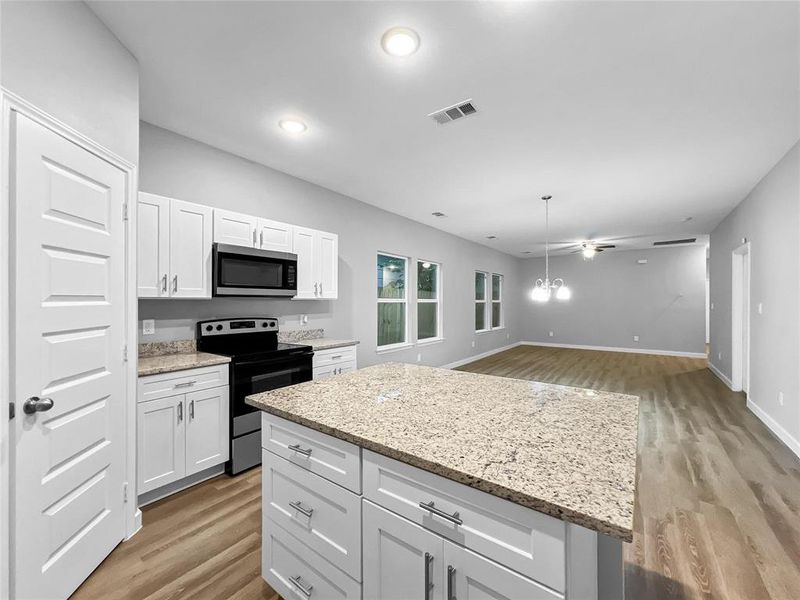 Kitchen with a center island, white cabinetry, light wood-type flooring, stainless steel appliances, and ceiling fan