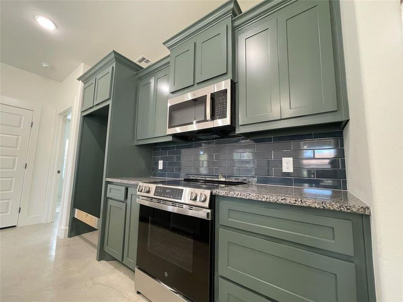 Kitchen featuring tasteful backsplash, green cabinetry, and stainless steel appliances