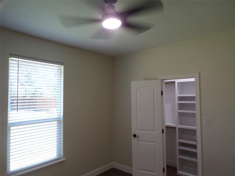 Unfurnished bedroom featuring multiple windows and ceiling fan