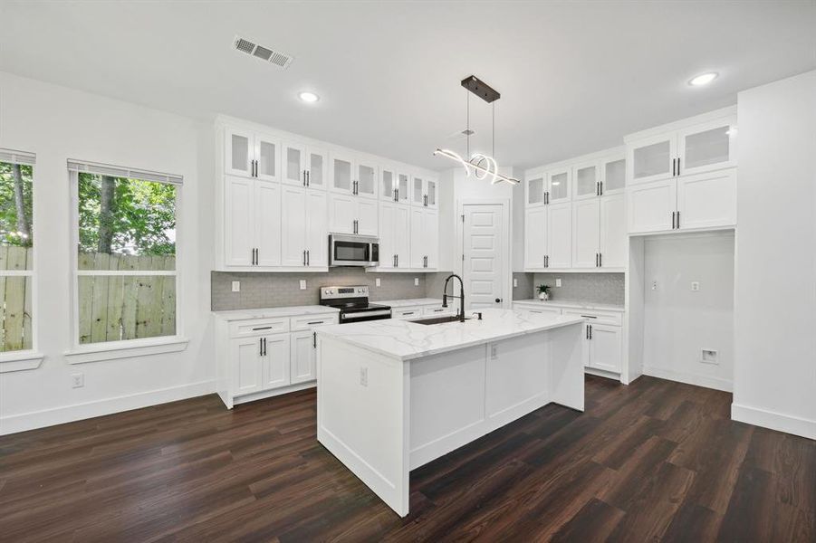 Kitchen featuring dark hardwood / wood-style floors, a kitchen island with sink, white cabinets, sink, and appliances with stainless steel finishes